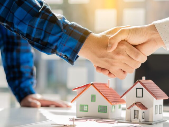 Real estate agent shakes hands with client after signing home purchase agreement after Finan has passed.